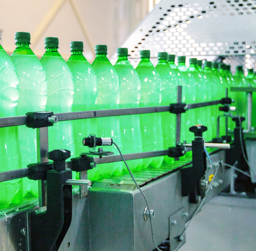 Green beverage bottles moving along an automated manufacturing conveyor line representing consumer goods production